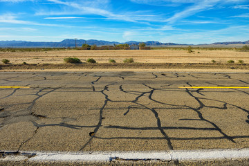 Fototapeta premium Repaired cracks, damaged asphalt on empty freeway through Nevada desert.