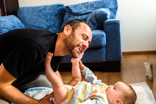 Father making funny gestures to his baby daughter while changing his diaper.