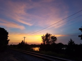 Fototapeta na wymiar Sunset over train tracks and a lake