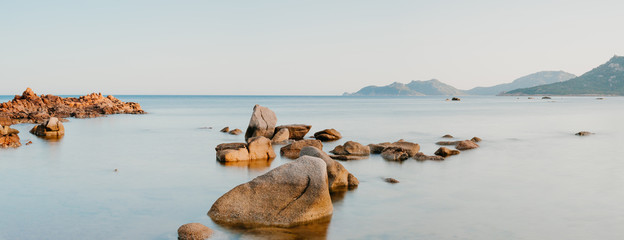Blick auf das weite ferne Meer mit Felsen und Steinen im Vordergrund im Wasser