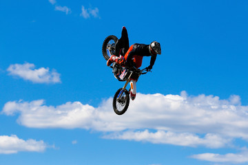 Fototapeta na wymiar JERSEY CITY, NJ - AUGUST 13, 2015: An unknown freestyle motocross rider soars through the air performing high-flying stunts on a motorcycle in Liberty State Park. The extreme sport is also called FMX.