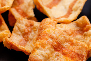 Chips salty bacon snack closeup details background. On black background. Close up.