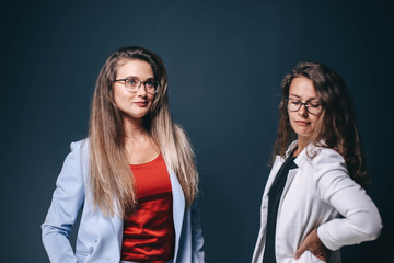 Two beautiful business women colleagues in office clothes in the studio. Women's fashion team corporation.