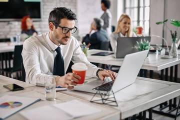 Young businessman drinking coffee while working on the computer.