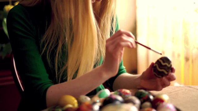 Beautiful young woman painting easter egg, super slow motion