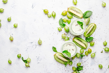Smoothies and milkshakes from gooseberry, milk cocktail with kiwi and yogurt? chia seeds, gray kitchen table background, flat lay, top view