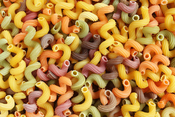 Food background - uncooked colorful Cavatappi (Celentani) durum wheat pasta with beetroot, spinach, carrot and tomato
