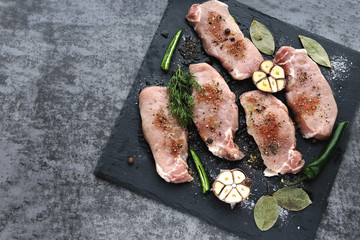 Raw pork steaks with garlic and spices on a stone board. The concept of cooking meat. Keto diet. Paleo diet. Pegan diet.