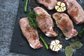 Raw pork steaks with garlic and spices on a stone board. The concept of cooking meat. Keto diet. Paleo diet. Pegan diet.