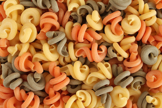 Food background - uncooked three-colored Trottole durum wheat pasta with basil and tomato