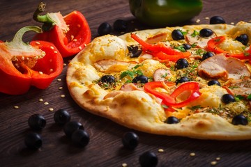 Vegetarian mushrooms Italian pizza with melted cheese, red pepper, corn, onion, black olives and fresh herb spices on a brown table decorated by mushrooms, black olives, red green pepper and arugula
