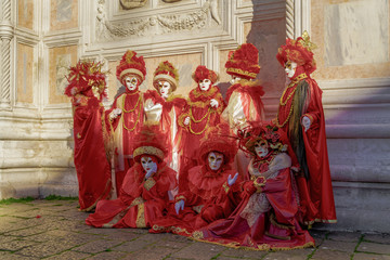 Naklejka premium Venice, Italy Carnival mask and costume poses in Campo San Zaccaria.Masked persons in traditional costume pose at a Venetian square during the Venice 2019 Carnival.