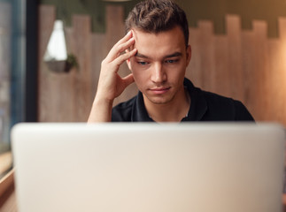 Pensive man watching laptop at table 