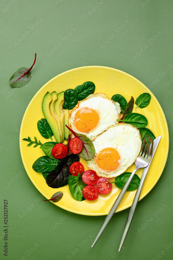 Wall mural Fried eggs with spinach tomatoes and greens