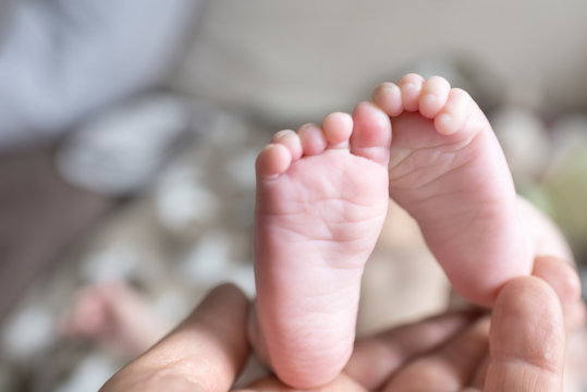 Feet of baby being held by mother's hand