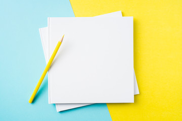 two white square notebook on yellow and blue paper