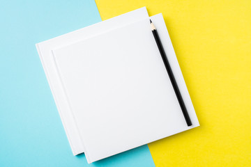 two white square notebook on yellow and blue paper