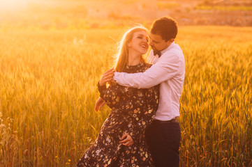 Man and woman embracing in wheat  field on the dusk