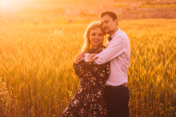 Man and woman embracing in wheat  field on the dusk