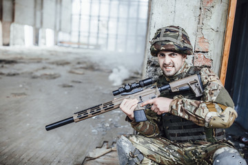 Military in the form holds in the hands of a big rifle,  looks like opponents from the corner