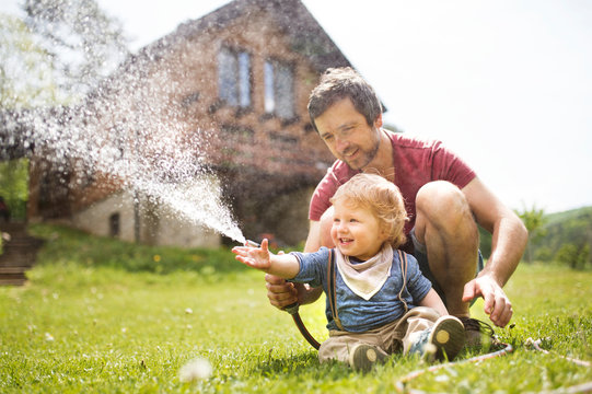 Little boy with his father watering the lawn