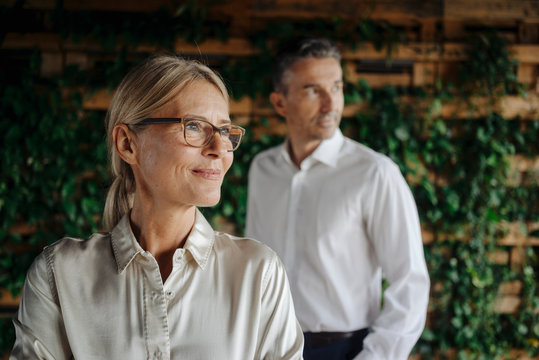 Businessman and businesswoman in green office thinking