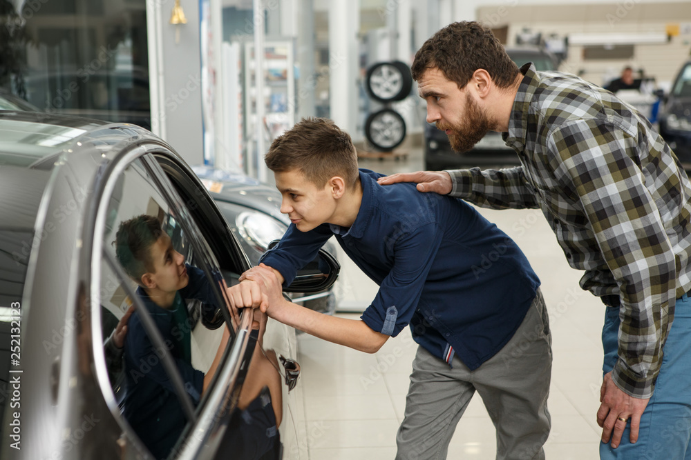 Wall mural Handsome mature man and his young son buying a new automobile together