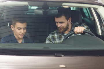 Handsome mature man and his young son buying a new automobile together