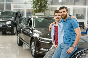 Fototapeta na wymiar Handsome mature man and his young son buying a new automobile together
