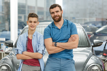 Handsome mature man and his young son buying a new automobile together