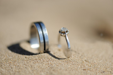 dos anillos de plata y brillante sobre la arena