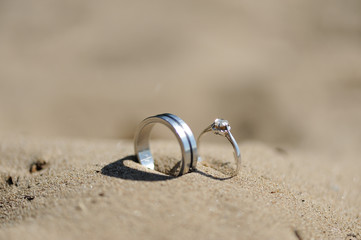 dos anillos de plata y brillante sobre la arena