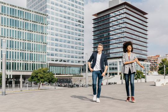 Two happy colleagues walking outside office building