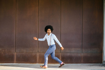 Portrait of man dancing in front of rusty metal wall