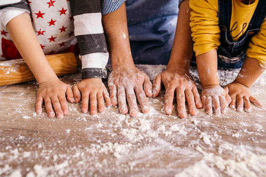 Mother and children with flour on their hands, partial view
