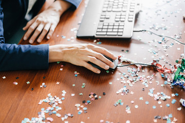 Hand of a woman working on a desk full of confetti