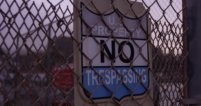 US Property No Tresspassing sign on rusty chainlink fence - rotating into view