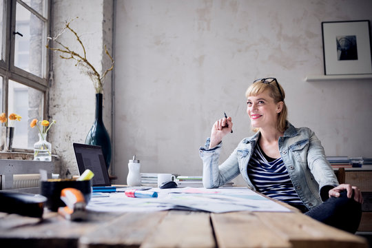 Portrait of laughing woman sitting at desk in a loft