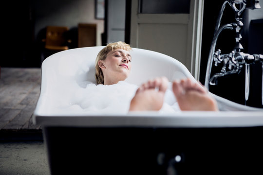 Blond woman taking bubble bath in a loft