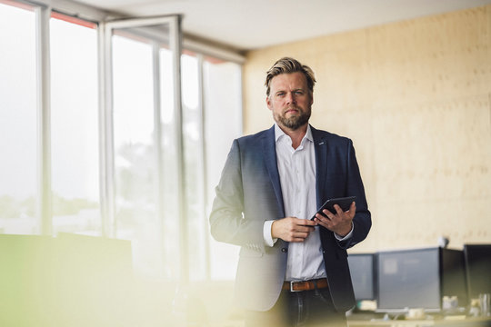 Businessman standing in office, using digital tablet