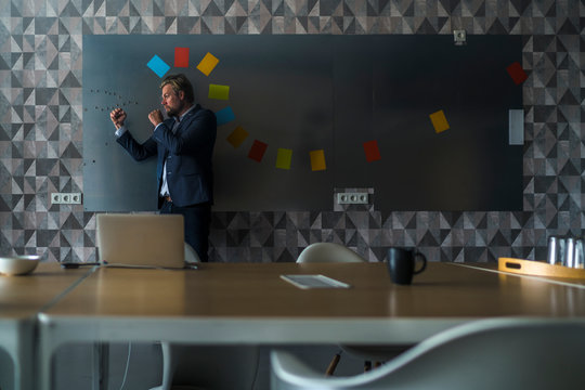 Businessman standing in front of magnet wall with a halo, made from sticky notes, roaring