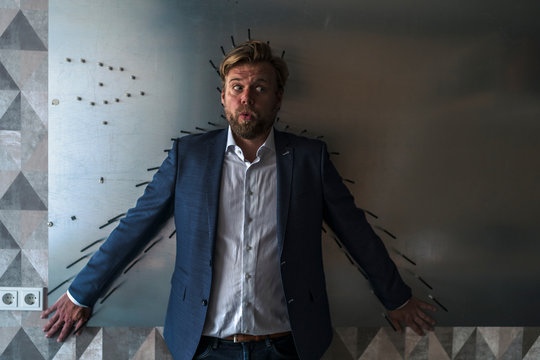 Businessman standing in boardroom with back to a magnet wall, framed by arrows