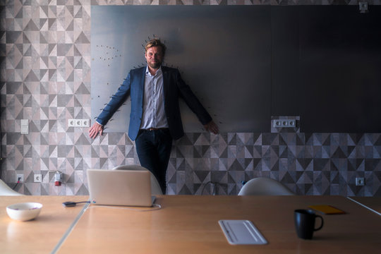 Businessman standing in boardroom with back to a magnet wall, framed by arrows