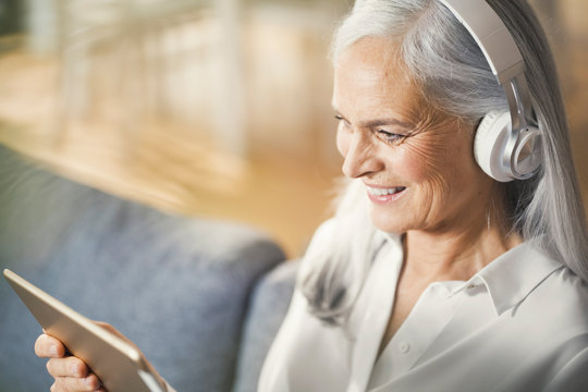 senior woman using digital tablet and headphones