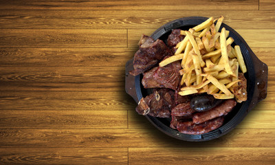 A beautiful plate of grilled steak and sausages with french fries on a wooden table