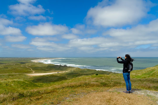 Denmark, Jutland, Bulbjerg, woman taking pictures in dune landscape