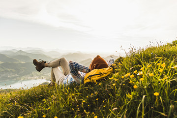 Woman lying on grass against cloudy sky