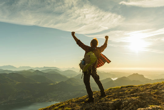 Austria, Salzkammergut, Hiker reaching summit, raising arms, cheering
