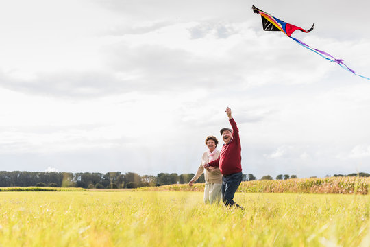 Happy senior couple flying kite in rural landscape