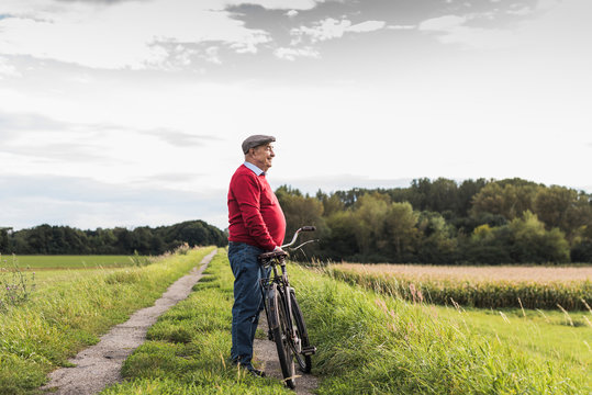 Senior man with bicycle in rural landscape